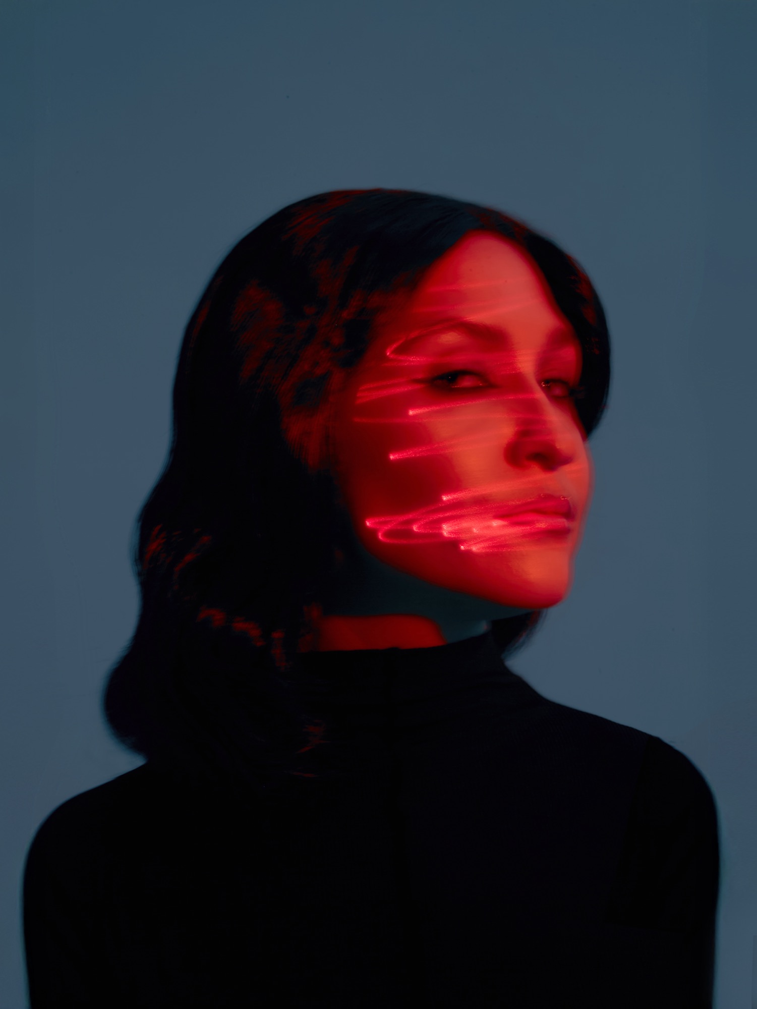 AYGYUL looking up, her face lit red against a blue background